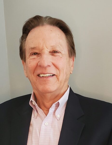 A man in a suit and tie smiling for the camera.